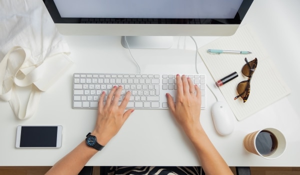 Mains qui tapent sur clavier d'ordinateur illustrant le télétravail