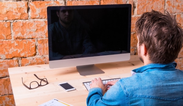 Homme qui travail assis un son bureau pour illustrer la sédentarité