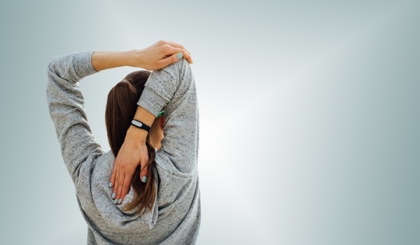 Femme de dos qui s'étire illustrant les exercices de renforcement musculaire en cas de lombalgie