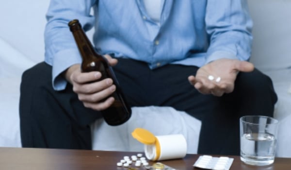 Homme qui tient de l'alcool et des médicaments illustrant les substances psychoactives