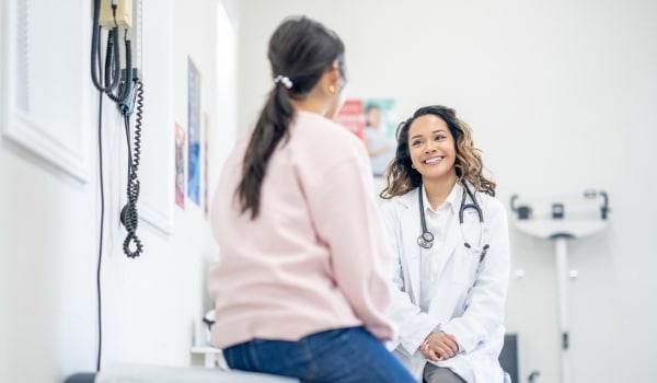 Médecin qui sourit à sa patient pour illustrer les nouveautés sur le suivi de l'état de santé des travailleurs