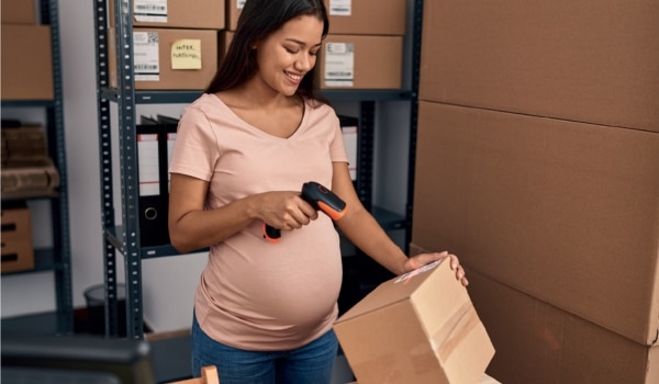 Femme enceinte qui scanne un carton au travail