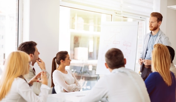 Personnes assises qui écoutent un homme debout illustrant les Actions de Formation et de Prévention des Salariés saisonniers