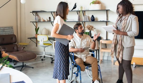 Homme en fauteuil roulant qui discute avec ses collègues de travail pour illustrer l'inaptitude et l'invalidité